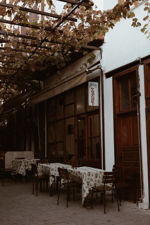 Free Cozy outdoor cafe with vine canopy and wooden doors, offering a quaint urban dining experience. Stock Photo