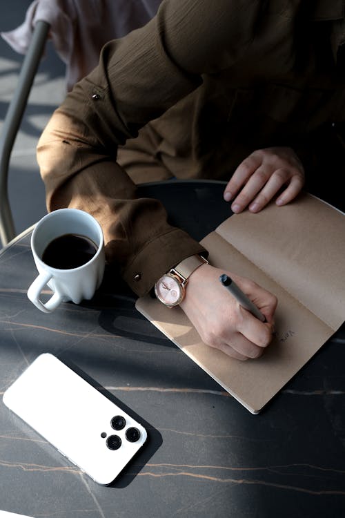 A Person Writing on a Notebook