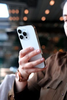 Close-up of a person holding a modern smartphone indoors, ideal for tech and lifestyle themes.
