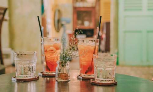 gratis Vier Helderglazen Drinkbekers Gevuld Met Oranje En Heldere Vloeistoffen Op Een Zwarte Ondergrond Stockfoto