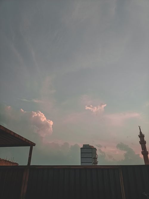 Free A skyline view featuring a tower and soft clouds during sunset, offering a moody atmosphere. Stock Photo