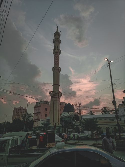 Free A striking minaret towers over an urban landscape during a vibrant sunset. Stock Photo