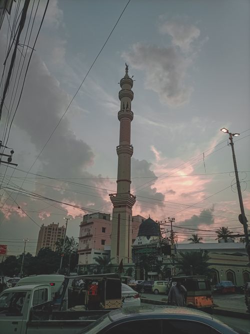 Free A towering minaret stands tall against a dramatic sunset sky in a bustling cityscape. Stock Photo