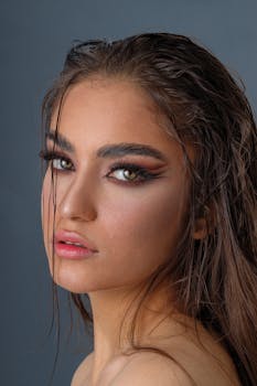 Close-up portrait of a young woman with striking makeup against a neutral background.