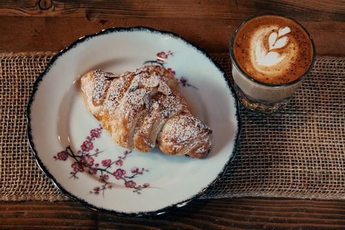 Free Delightful croissant and cappuccino on a rustic table setting. Perfect morning breakfast scene. Stock Photo