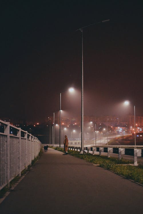 Person Standing on Sidewalk at Night