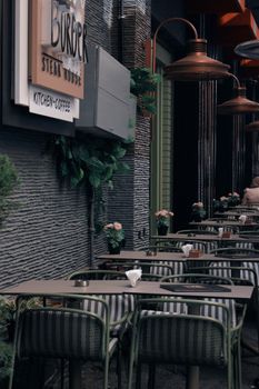 Modern outdoor cafe with stylish furniture and ambient lighting on an urban sidewalk.