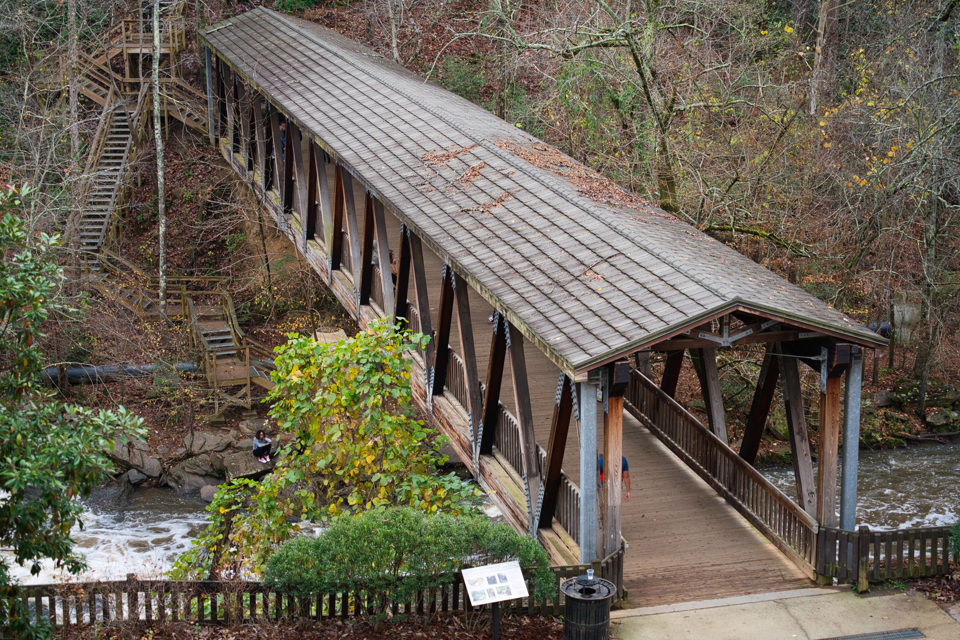 Scenic view of a historic covered bridge at Roswell Mill, GA, surrounded by autumn foliage.