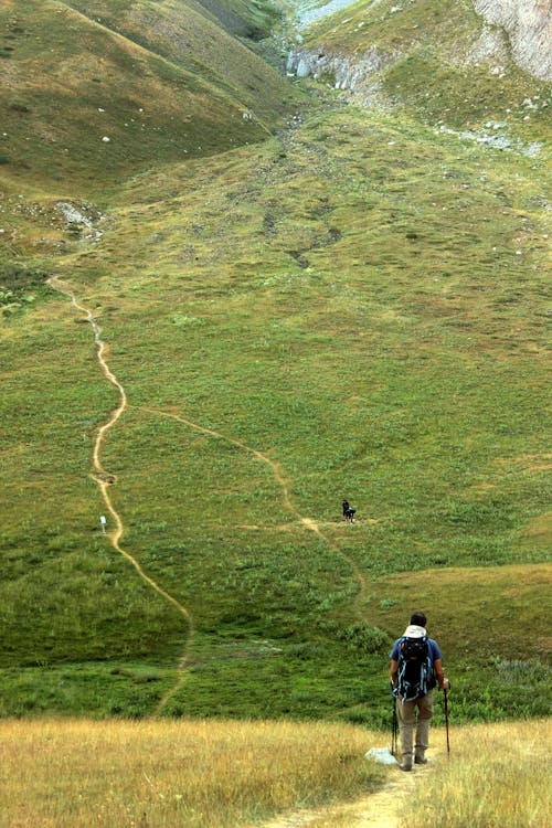 Man Hiking on Path Between Hills