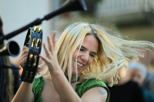 Woman in Green Blouse Playing a Tambourine