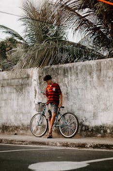 A young man with a bicycle checks his cellphone on a street in Maracanaú, Brazil.