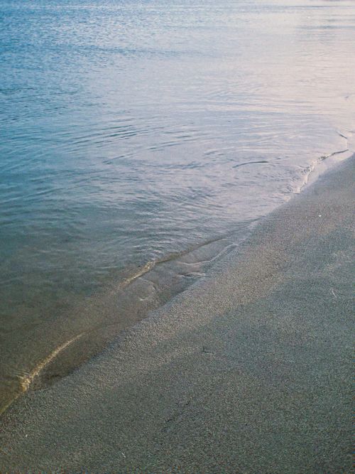 Free Peaceful view of a sandy beach meeting clear sea waters in Italy during sunset. Stock Photo