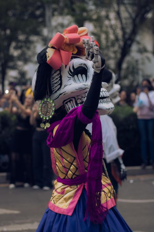 Free Vibrant Day of the Dead celebration with colorful costumes and skeleton masks in a festive parade. Stock Photo