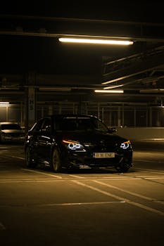 Modern black car parked in a dimly lit urban parking garage, showcasing a sleek and mysterious atmosphere.