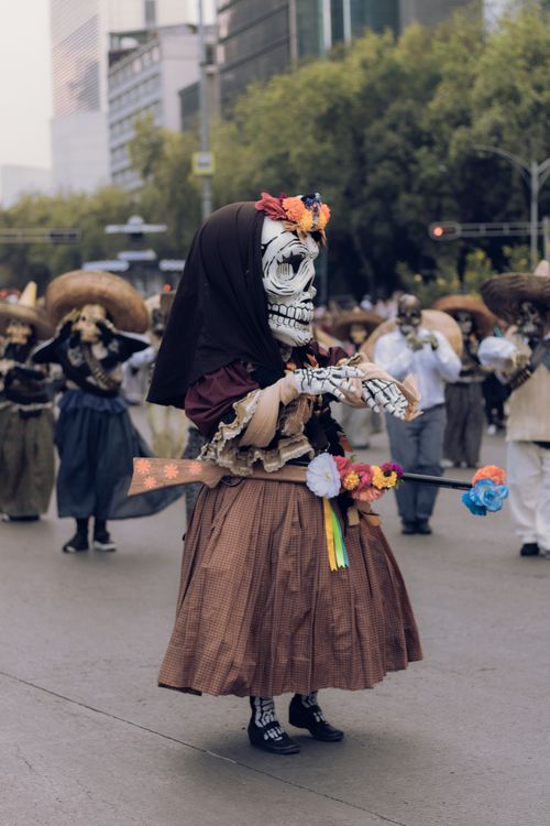 Free Skeleton costumes and vibrant decorations at a Day of the Dead parade in the city. Stock Photo
