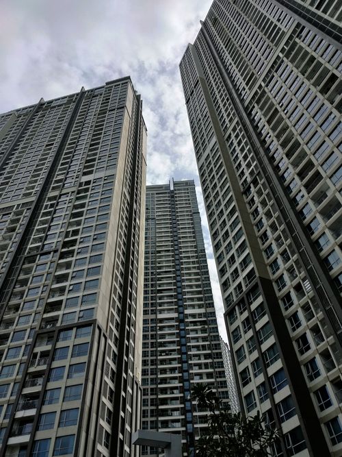 Free Low angle view of towering skyscrapers against a cloudy sky in a bustling urban cityscape. Stock Photo