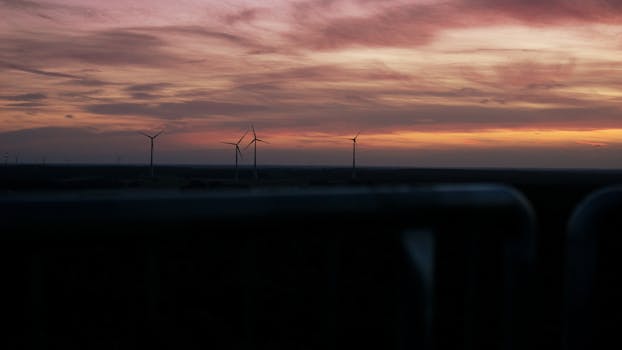 Silhouetted wind turbines against a vibrant sunset sky in Reken, Germany.