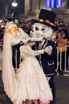 Couple in Dia de Muertos costumes dancing at a colorful night festival in Mexico.