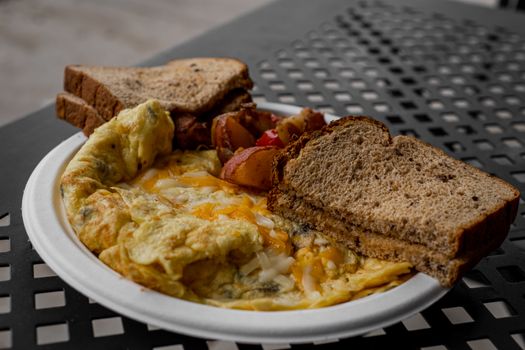 Delicious breakfast featuring an omelette, toast, and roasted potatoes on a white plate.
