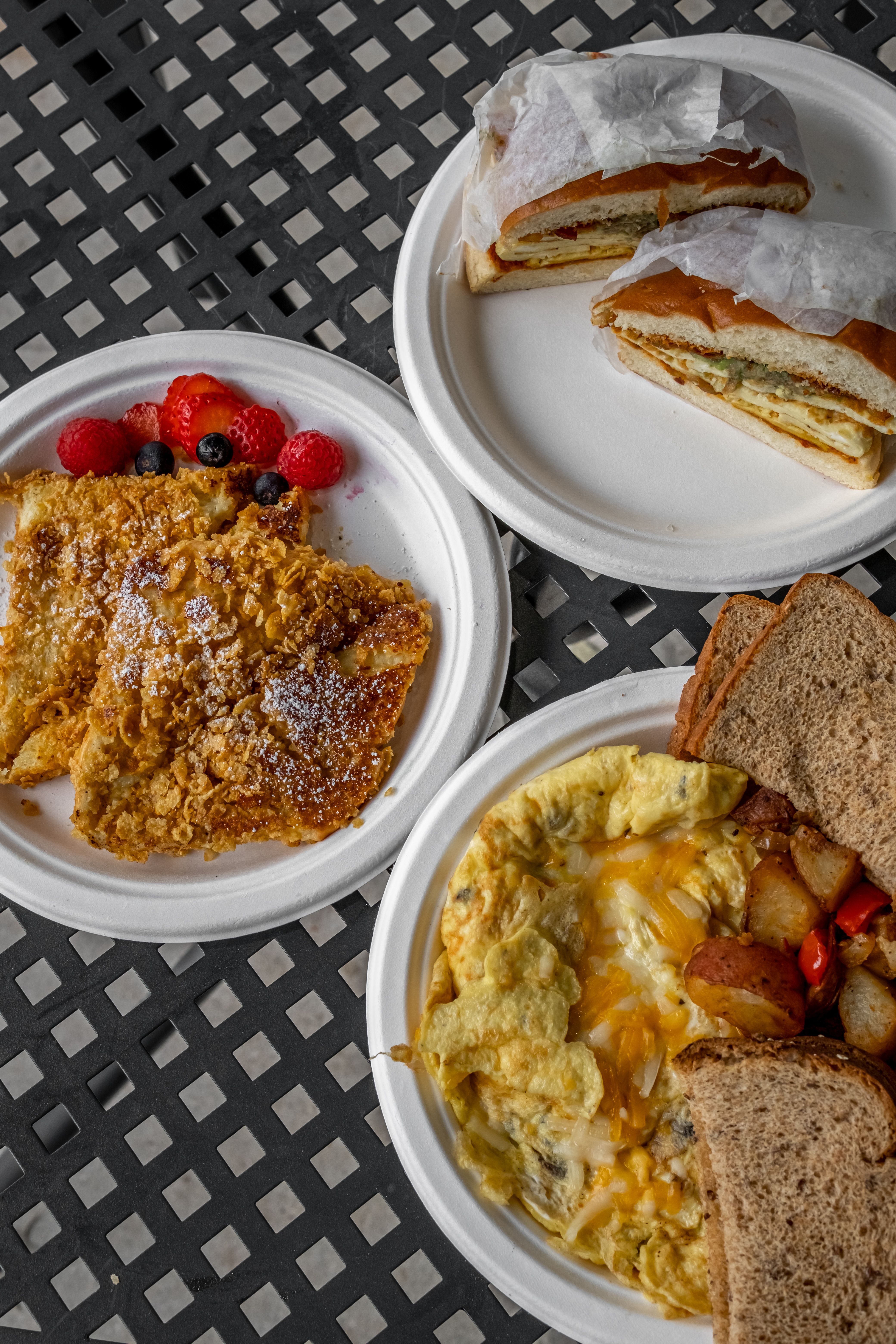 Flat lay of a delicious breakfast spread featuring French toast, omelette, and fresh berries for a hearty meal.