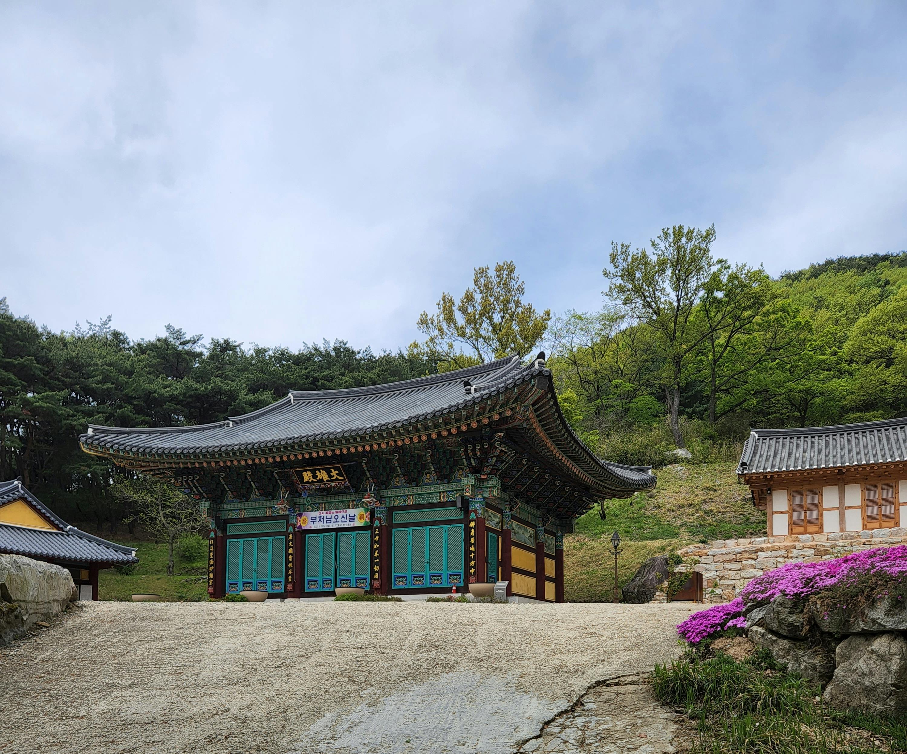 A serene view of a traditional Korean temple surrounded by vibrant spring foliage.