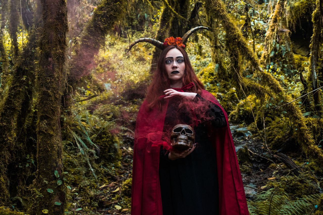 a captivating portrait of a witch holding a skull in a mystical forest