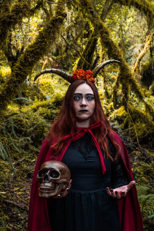 Free Captivating portrait of a witch with horns in a mystical forest, holding a skull. Stock Photo