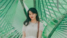 一名年轻女子以户外充满活力的背景为衬托，用大绿叶摆出姿势