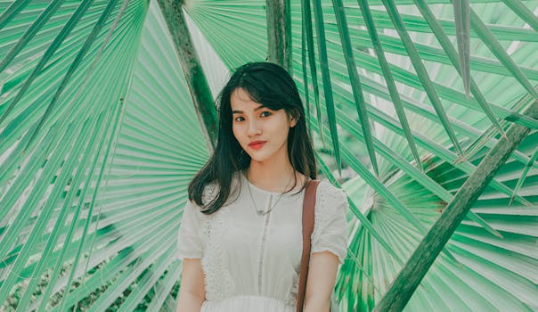 一名年轻女子以户外充满活力的背景为衬托，用大绿叶摆出姿势