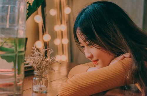 Free Young woman relaxing indoors with a smile and ambient lighting. Perfect for lifestyle imagery. Stock Photo