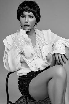 Classic monochrome portrait of a stylish woman posing in a studio setting, showcasing elegance and grace.