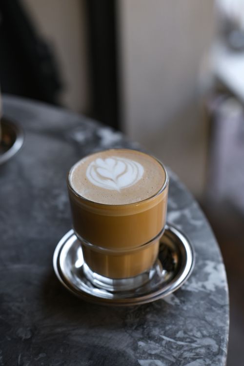 Free A beautifully crafted latte with art, served in a glass cup on a marble surface. Stock Photo