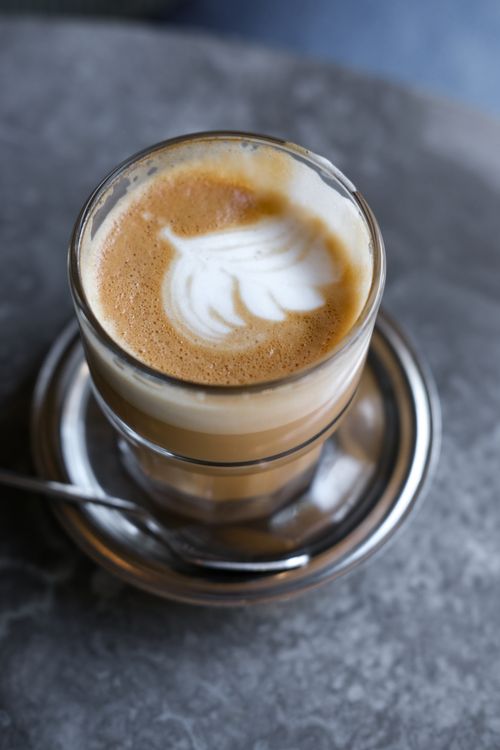 Free Elegant glass coffee cup with latte art on a saucer, perfect for coffee lovers. Stock Photo