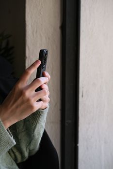 Close-up of hands holding a smartphone indoors near a window, soft ambient lighting.