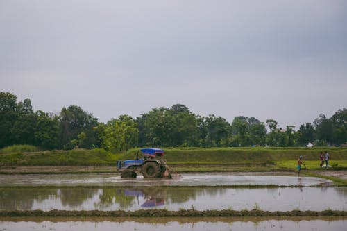 A Heavy Equipment Machine Tractor Plowing Soil on Paddy Field