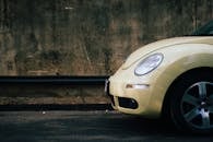 在城市环境中，一辆黄色的大众甲壳虫停在一堵坚固的墙上