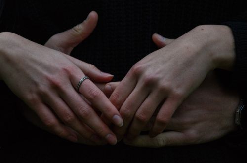Free Intimate close-up of a couple's intertwined hands, one with a ring. Stock Photo