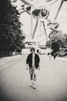 Casual black and white photo of a man walking near Atomium, Brussels.