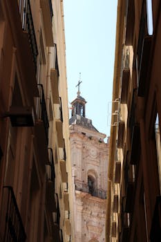 View of a historic church tower through narrow Málaga alleyways.