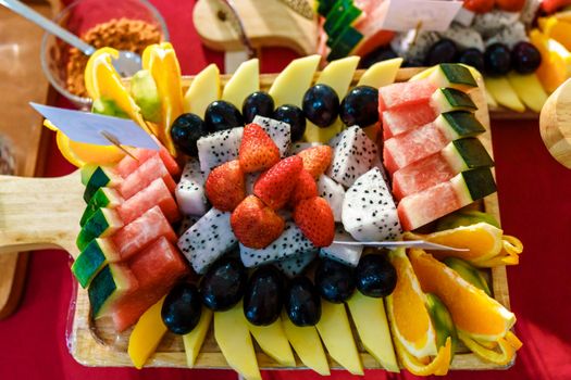 Vibrant assortment of fresh tropical fruits artfully arranged on a wooden board.