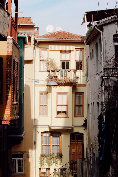 Free Sunlit urban apartment facade with balcony and classic architecture. Stock Photo