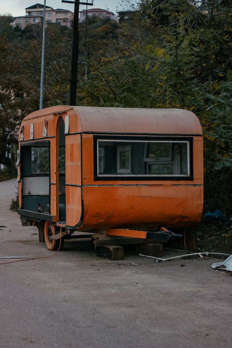 A Dilapidated Orange Train Wagon On Road