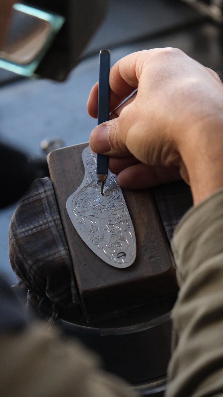 Close-up Of Man Engraving A Pattern In Metal 