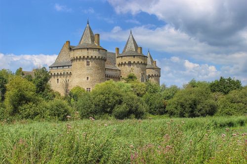 Free A stunning view of the medieval Chateau de Suscinio, surrounded by lush greenery under a vibrant sky. Stock Photo