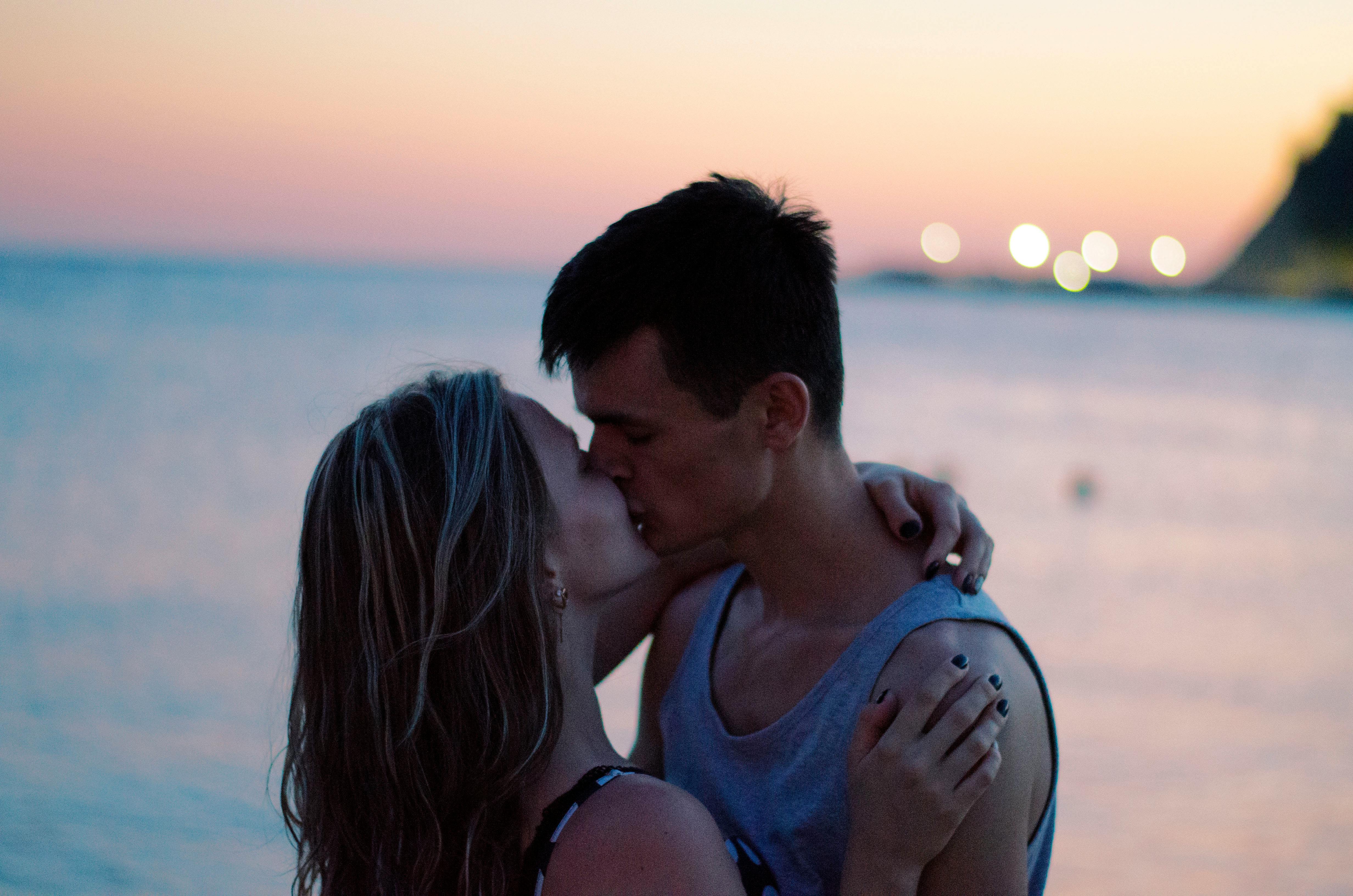 Selective Focus Photography of Couple Kissing on Shore