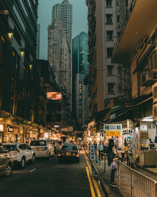 Vehicle on Street in Between High-rise Buildings With Stores on the Bottom