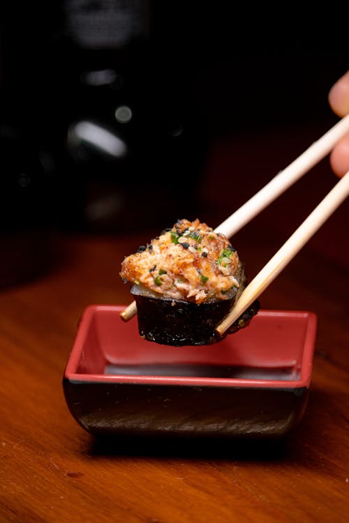Close-up of Person Holding a Piece of Sushi with Chopsticks