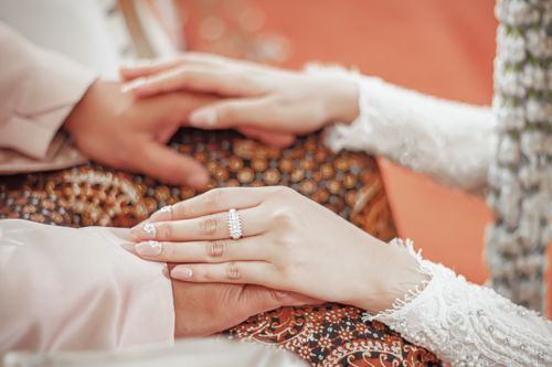 Free Close-up of a bride and groom holding hands, showcasing elegant jewelry and intricate henna designs. Stock Photo