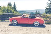 Red Convertible Coupe Parked Near Wooden Fence Overlooking Trees