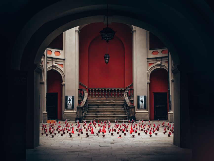 Intricate archway leading to red walls and stairs adorned with red flags.